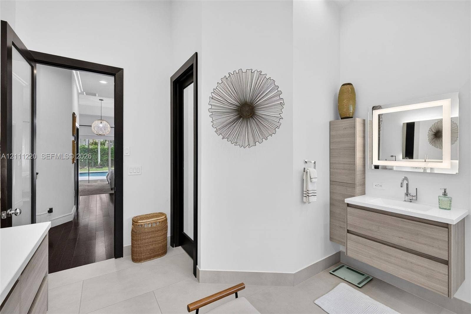 134 Dockside Terrace, Weston, FL 33327 Floating vanity with wood-finish cabinetry, integrated countertop, and LED-backlit mirror