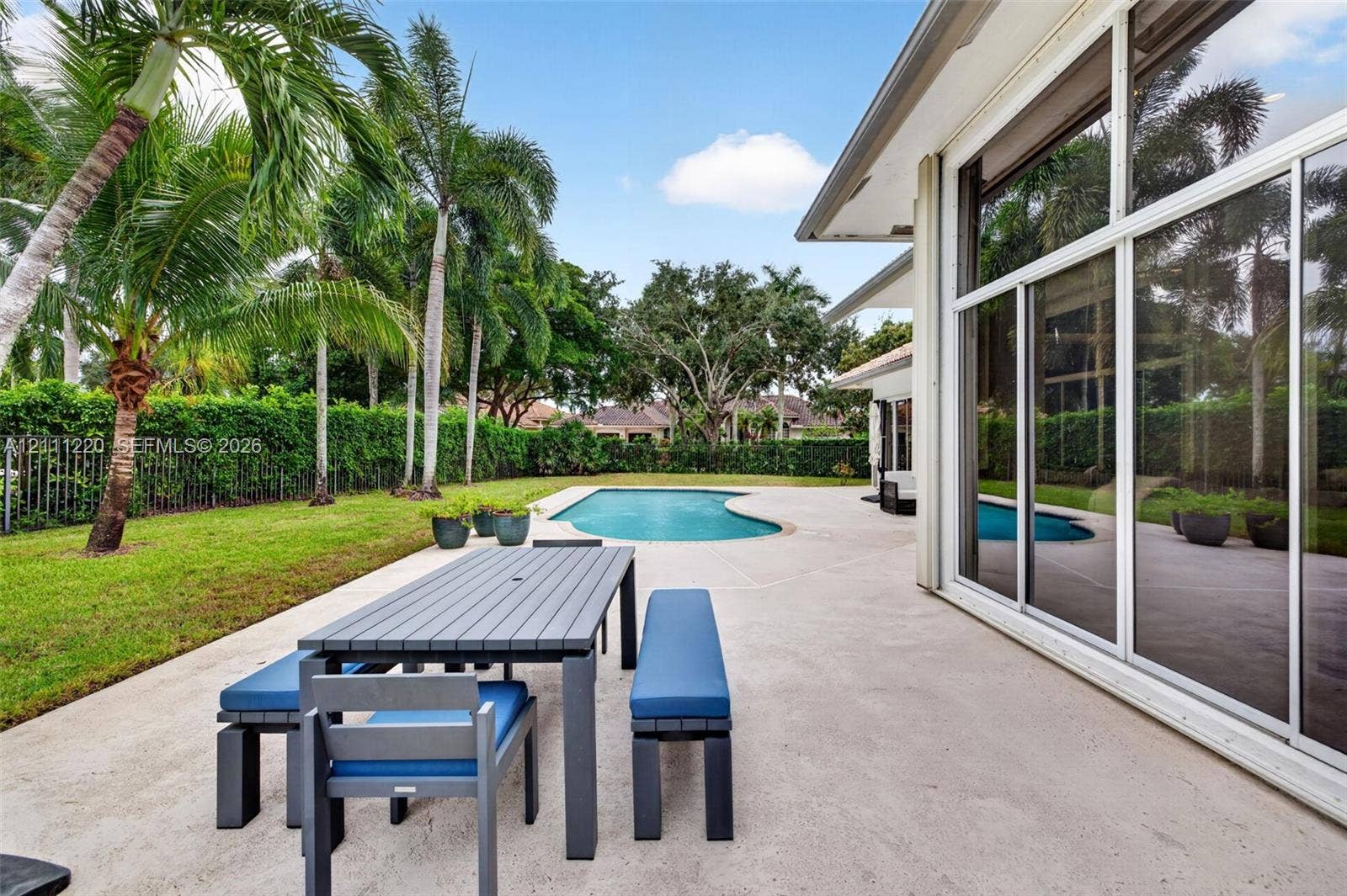 134 Dockside Terrace, Weston, FL 33327 Rear patio featuring expansive concrete decking, in-ground swimming pool, palm trees, and full-height sliding glass doors
