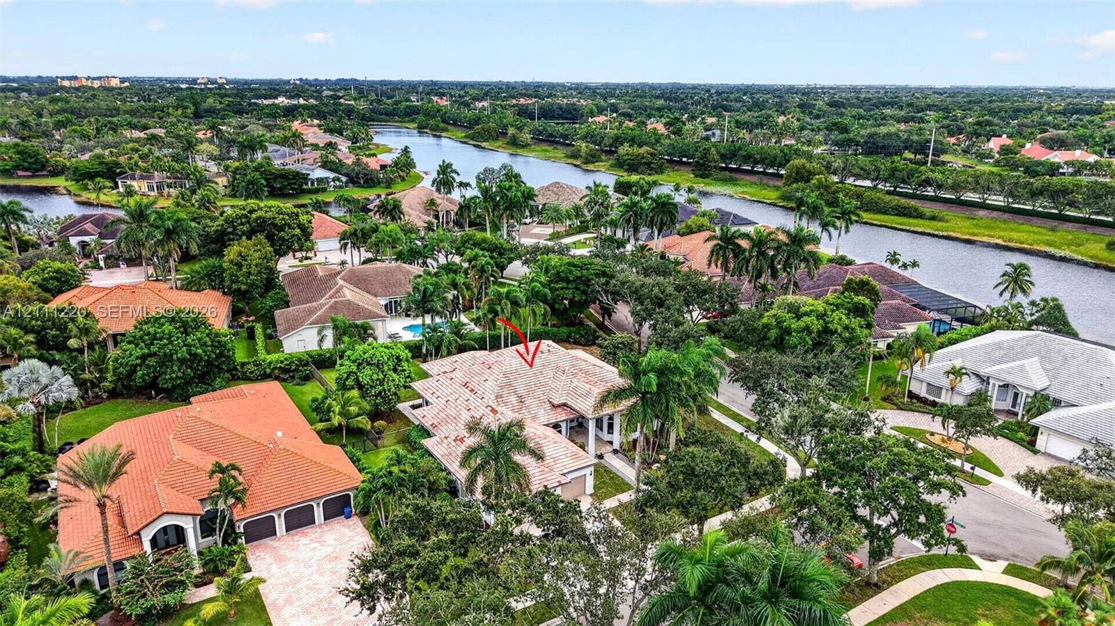 134 Dockside Terrace, Weston, FL 33327 Aerial perspective of a multi-hip tile roof residence featuring a paved driveway, multi-car garage, covered entryway, and mature palm landscaping