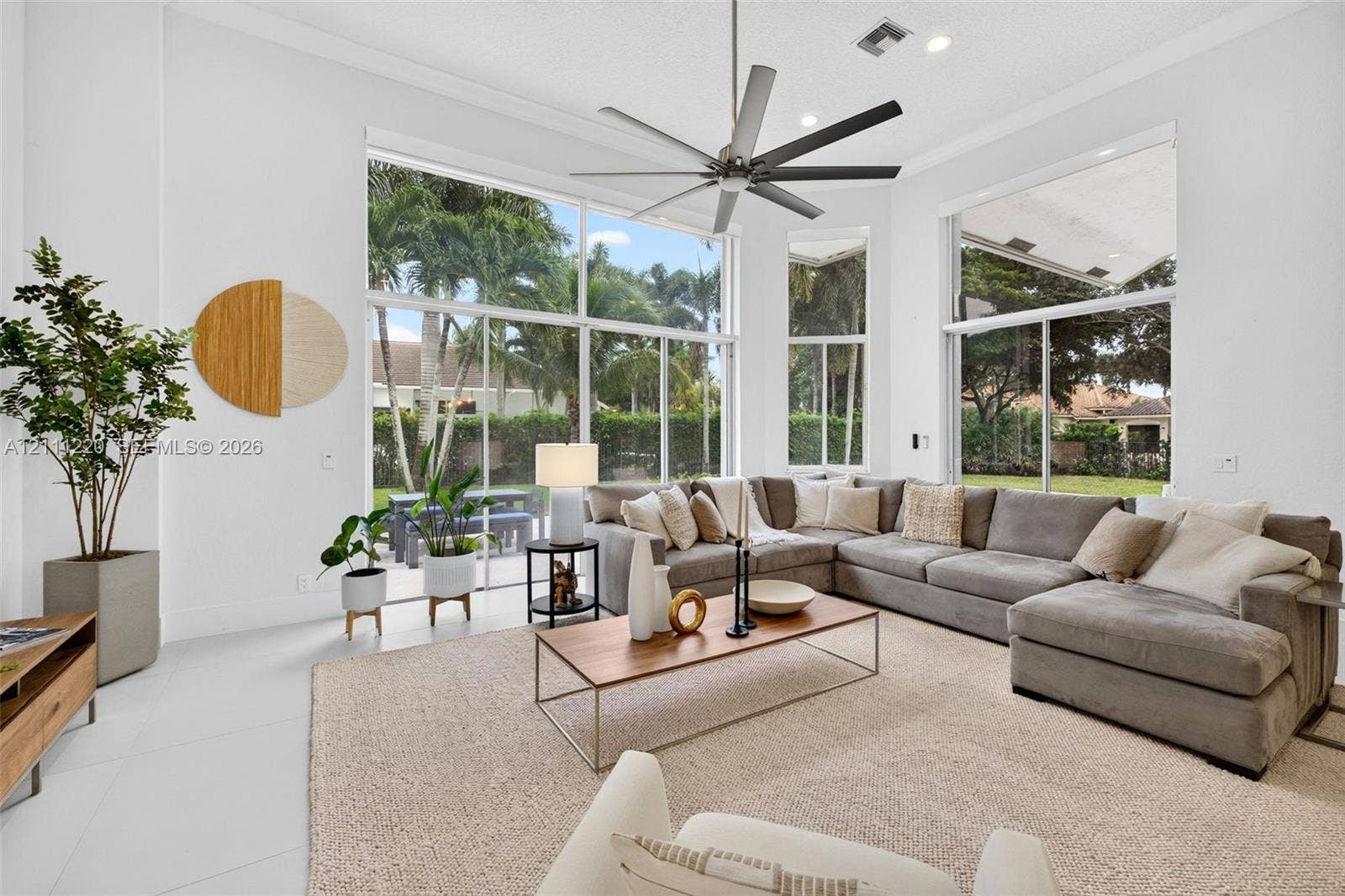 134 Dockside Terrace, Weston, FL 33327 Expansive living area featuring vaulted ceilings, floor-to-ceiling windows, polished neutral flooring, and a multi-blade ceiling fan