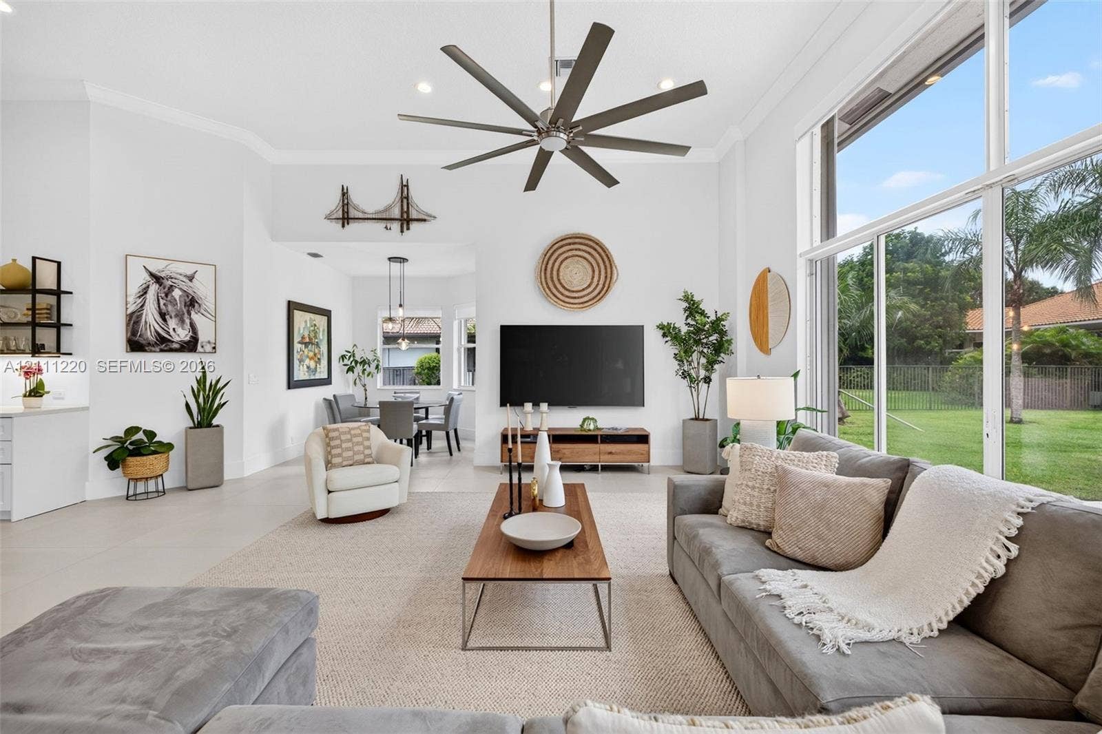 134 Dockside Terrace, Weston, FL 33327 High ceilings featuring a large multi-blade ceiling fan, expansive floor-to-ceiling windows, and neutral oversized floor tiling