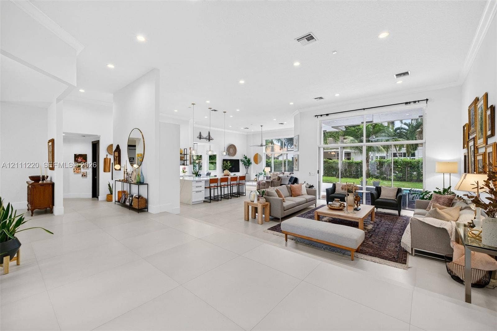 134 Dockside Terrace, Weston, FL 33327 Open-concept living space featuring oversized neutral floor tile, recessed lighting, crown molding, and expansive floor-to-ceiling glass panel windows