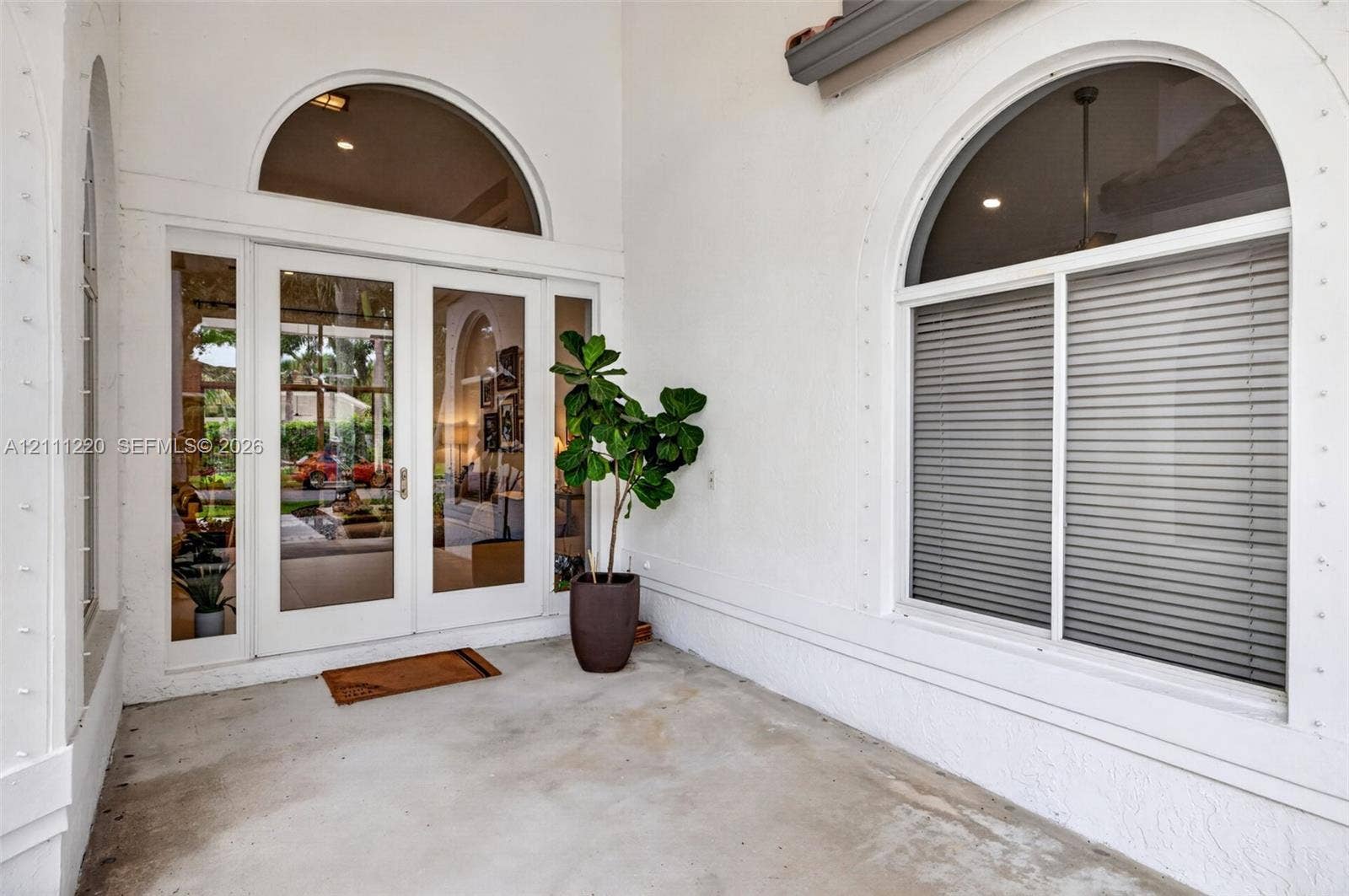 134 Dockside Terrace, Weston, FL 33327 Covered entryway featuring double-glass doors, arched transom windows, and white stucco exterior finish
