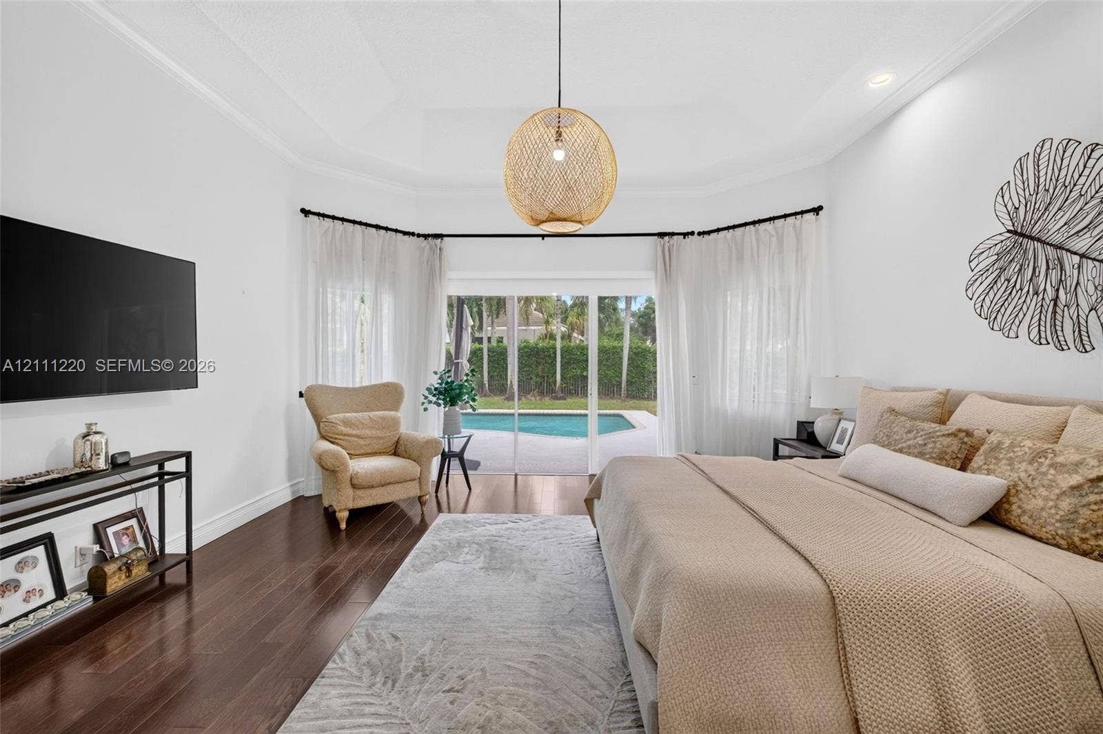 134 Dockside Terrace, Weston, FL 33327 Tray ceiling, wood-finish flooring, and glass sliding doors providing exterior exposure to a swimming pool