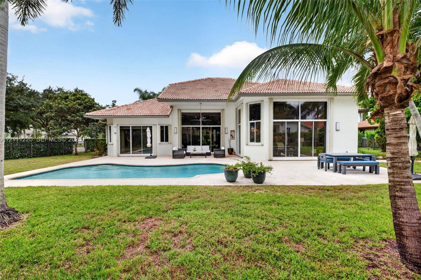 134 Dockside Terrace, Weston, FL 33327 Rear exterior featuring a tile roof, stucco finish, in-ground swimming pool, concrete patio, and floor-to-ceiling glass panel doors