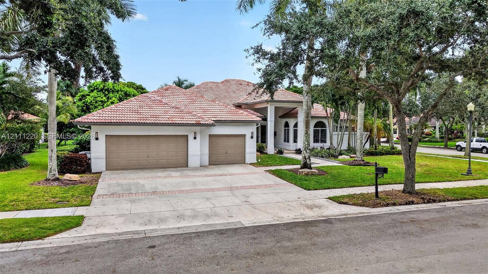 134 Dockside Terrace, Weston, FL 33327 Exterior featuring a multi-gabled tile roof, stucco facade, arched windows, and a three-car garage with a paved driveway