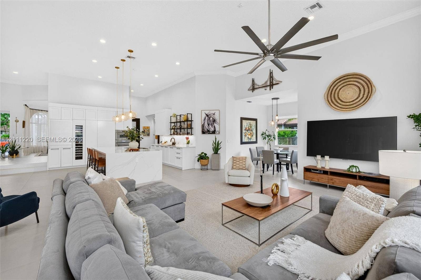 134 Dockside Terrace, Weston, FL 33327 Open-concept living space featuring high ceilings, a center island with waterfall-edge countertop, recessed lighting, multi-blade ceiling fan, and large-format tile flooring