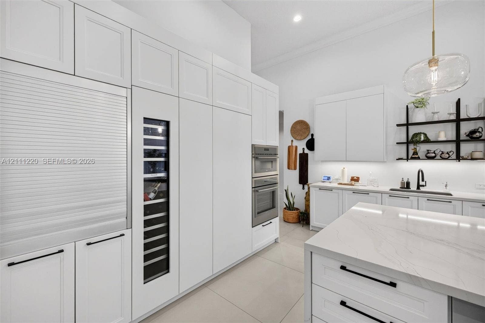 134 Dockside Terrace, Weston, FL 33327 Kitchen featuring white shaker-style cabinetry, floor-to-ceiling panel-ready appliances, a built-in wine cooler, wall-mounted double ovens, and a central island with a stone-finish countertop