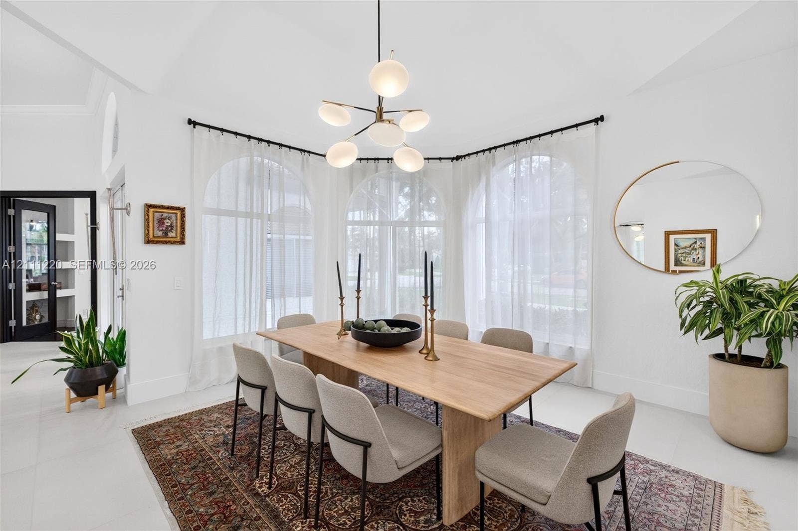 134 Dockside Terrace, Weston, FL 33327 Dining area featuring three large arched windows, vaulted ceiling, and a modern multi-globe chandelier with a metal finish