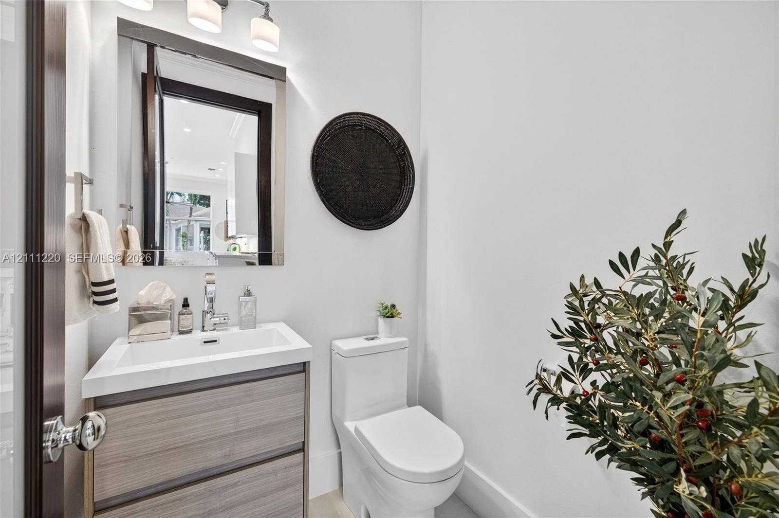 134 Dockside Terrace, Weston, FL 33327 Vanity with a rectangular basin, wood-finish cabinetry, wall-mounted mirror, three-light fixture, and dual-flush toilet
