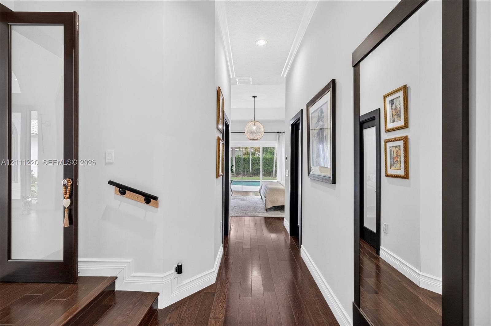 134 Dockside Terrace, Weston, FL 33327 Hallway featuring dark wood-finish flooring, high ceilings with recessed lighting, crown molding, a decorative globe pendant fixture, and glass-paneled doors with dark frames