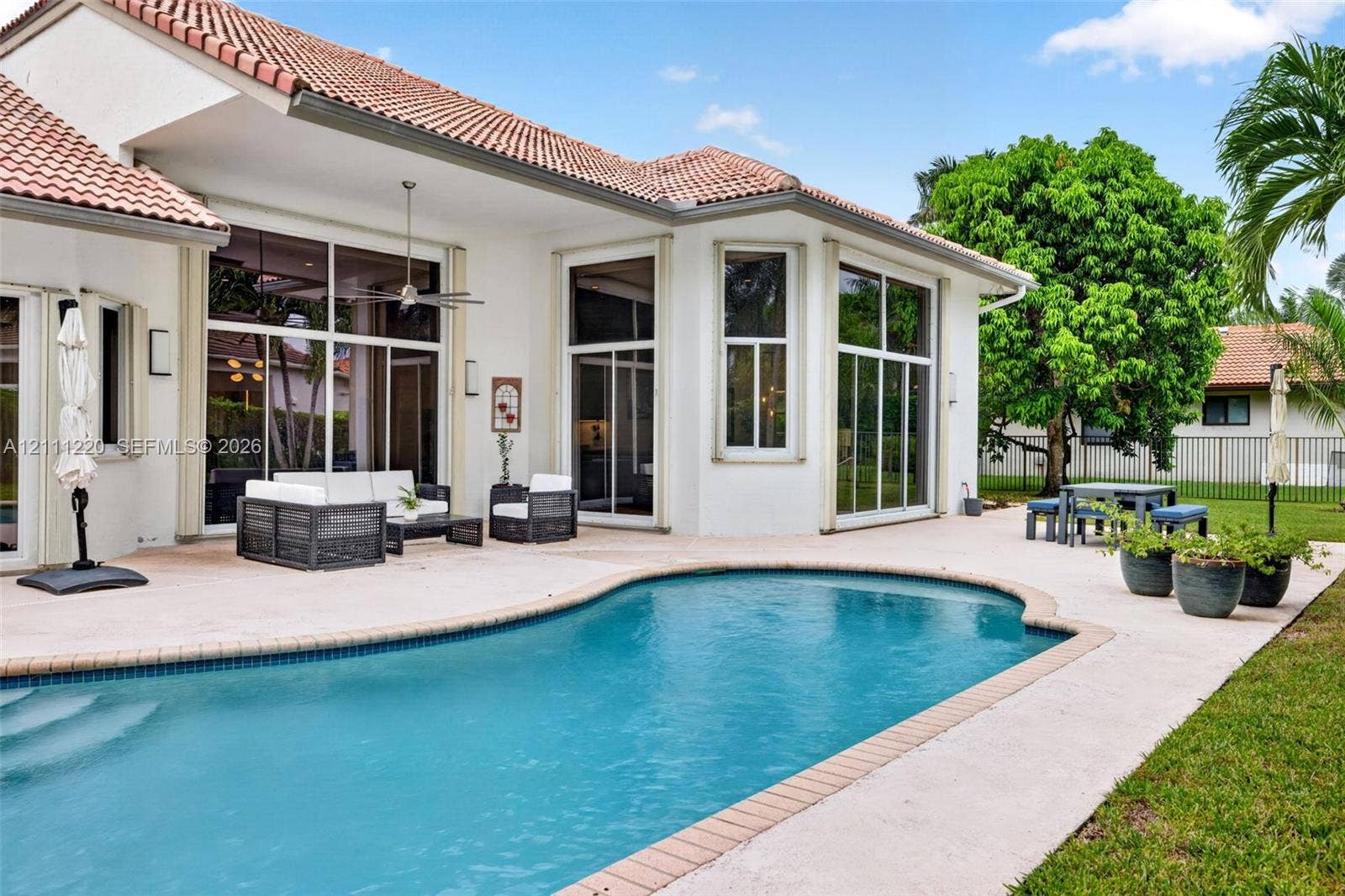 134 Dockside Terrace, Weston, FL 33327 Stucco exterior featuring a clay tile roof, expansive concrete patio, and in-ground pool with stone coping