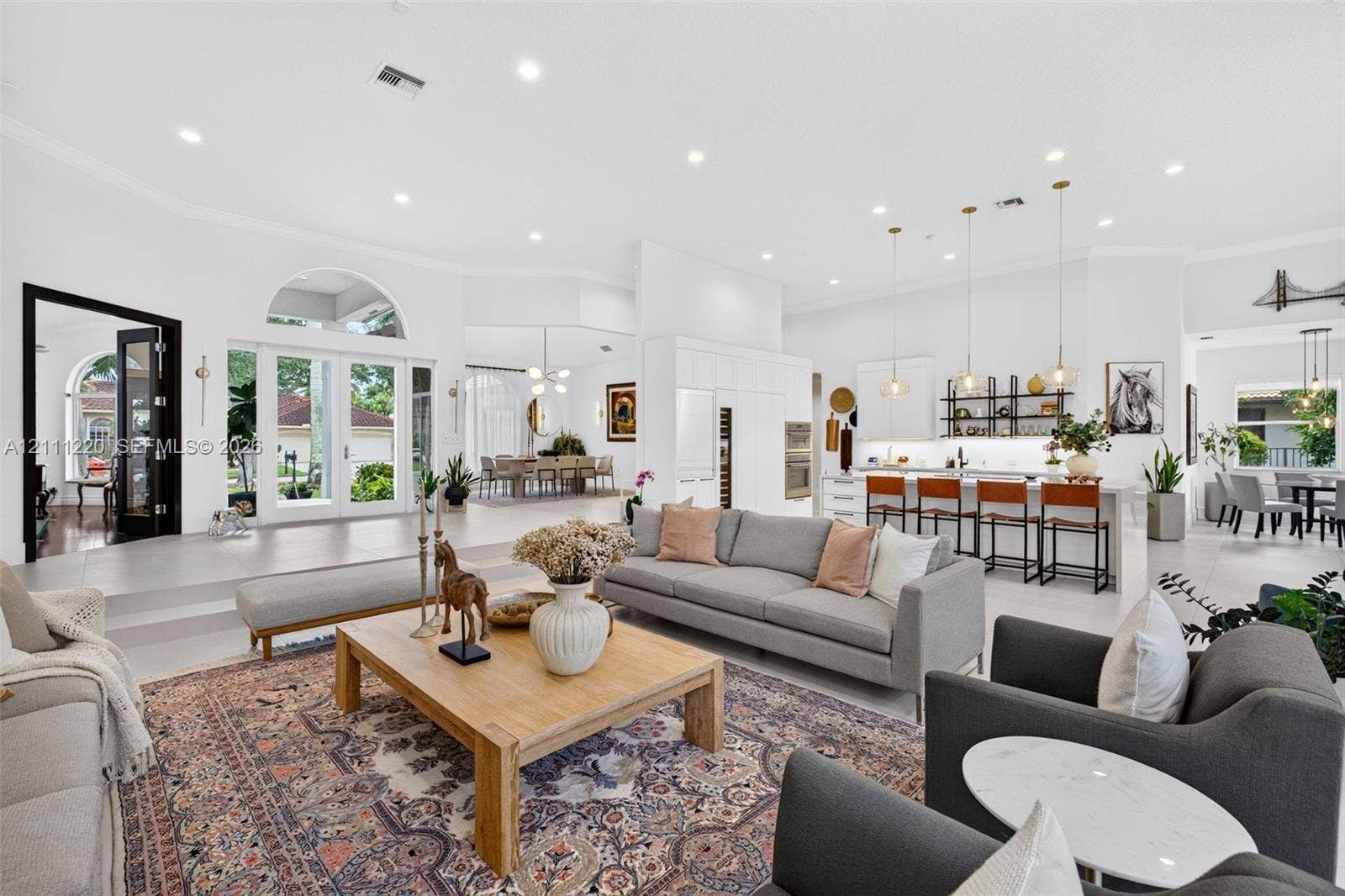 134 Dockside Terrace, Weston, FL 33327 Open-concept interior featuring large-format tile flooring, recessed lighting, arched window accents, double glass-paned doors, and a kitchen island with pendant lighting