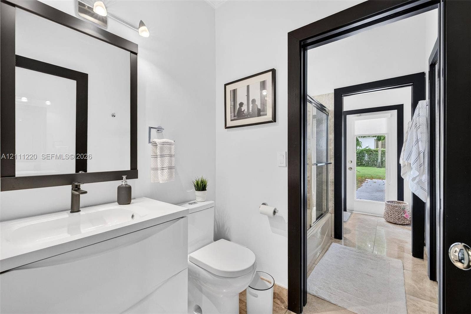 134 Dockside Terrace, Weston, FL 33327 Bathroom featuring a white vanity with an integrated sink, dark-finish faucet, framed wall-mounted mirror, and black door casings