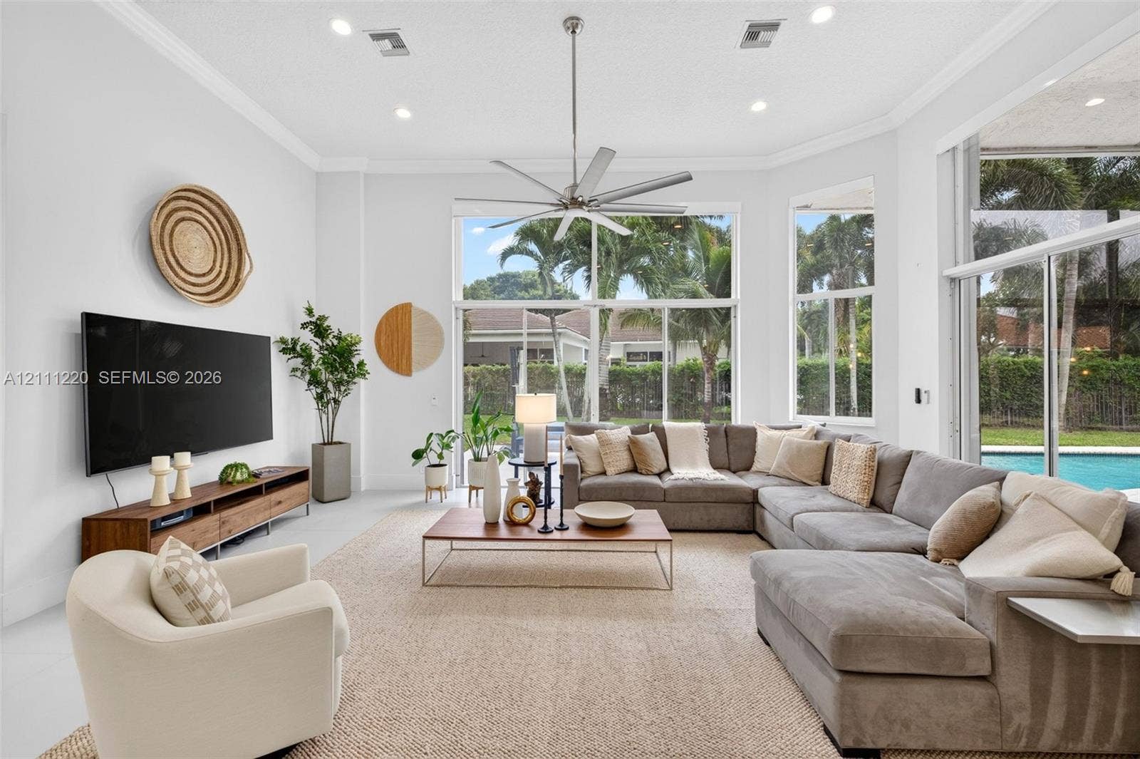 134 Dockside Terrace, Weston, FL 33327 Living space featuring high ceilings, recessed lighting, crown molding, a central ceiling fan, and floor-to-ceiling windows with sliding glass doors