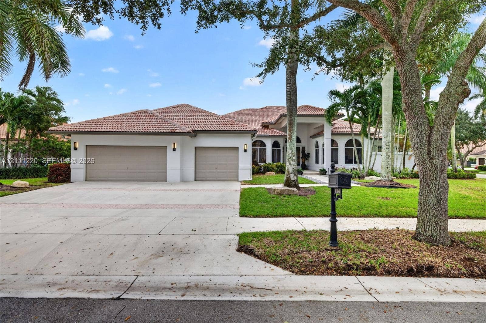 134 Dockside Terrace, Weston, FL 33327 Stucco exterior featuring a multi-car garage, tiled roof, arched window detailing, and manicured landscaping