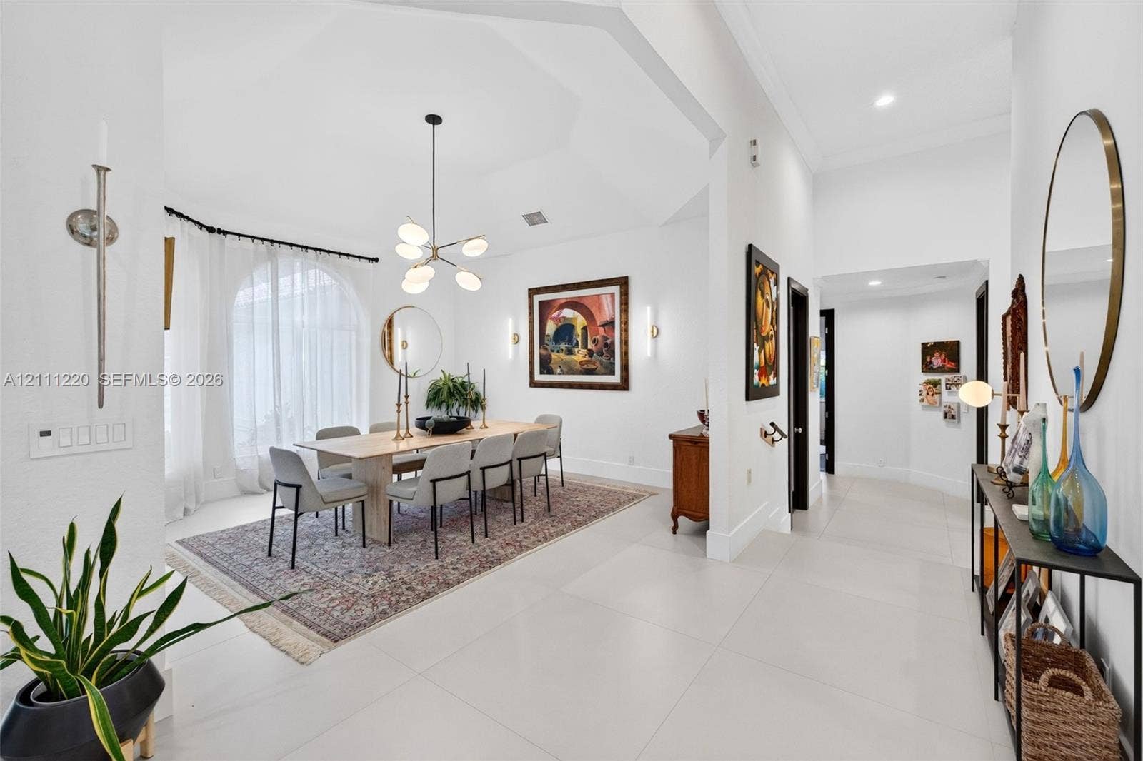 134 Dockside Terrace, Weston, FL 33327 Dining area featuring a vaulted ceiling, arched window, oversized tile flooring, and a multi-arm chandelier
