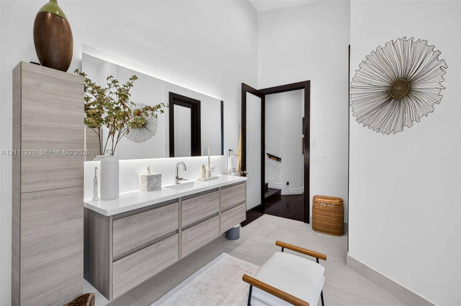 134 Dockside Terrace, Weston, FL 33327 Floating vanity with wood-finish cabinetry, solid-surface countertop, integrated rectangular sink, wall-to-wall mirror with integrated LED backlighting, and floor-to-ceiling cabinetry