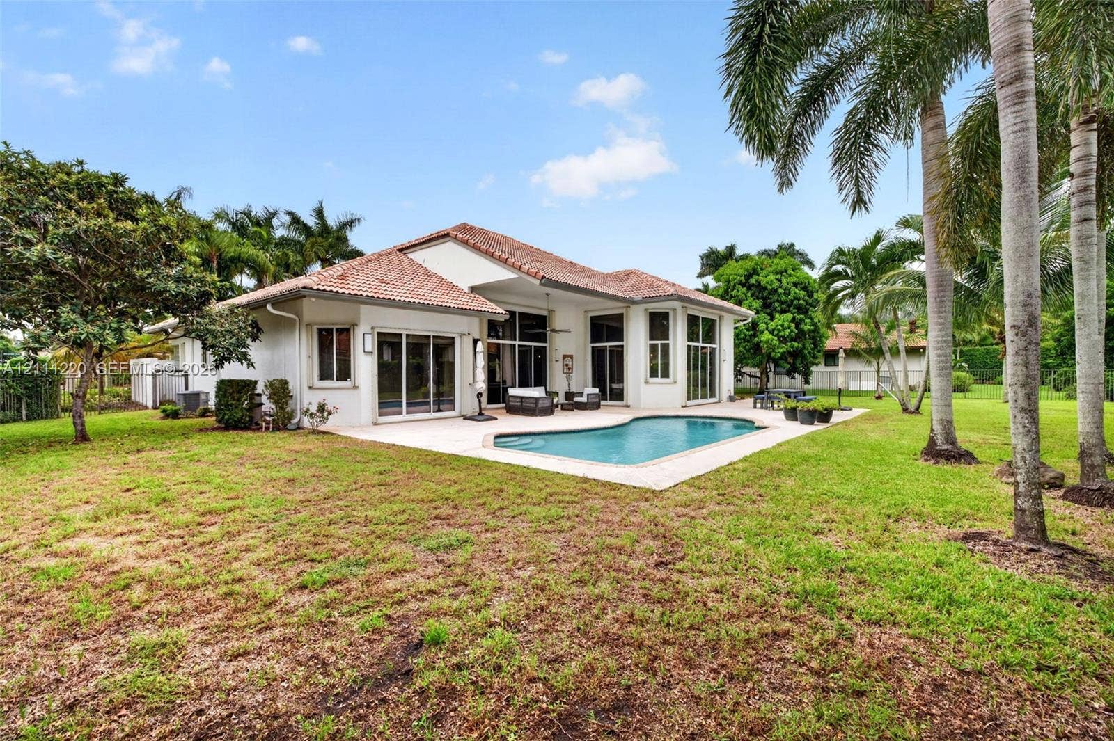 134 Dockside Terrace, Weston, FL 33327 Stucco exterior featuring a clay tile roof, expansive concrete pool deck, in-ground swimming pool, and mature landscaping
