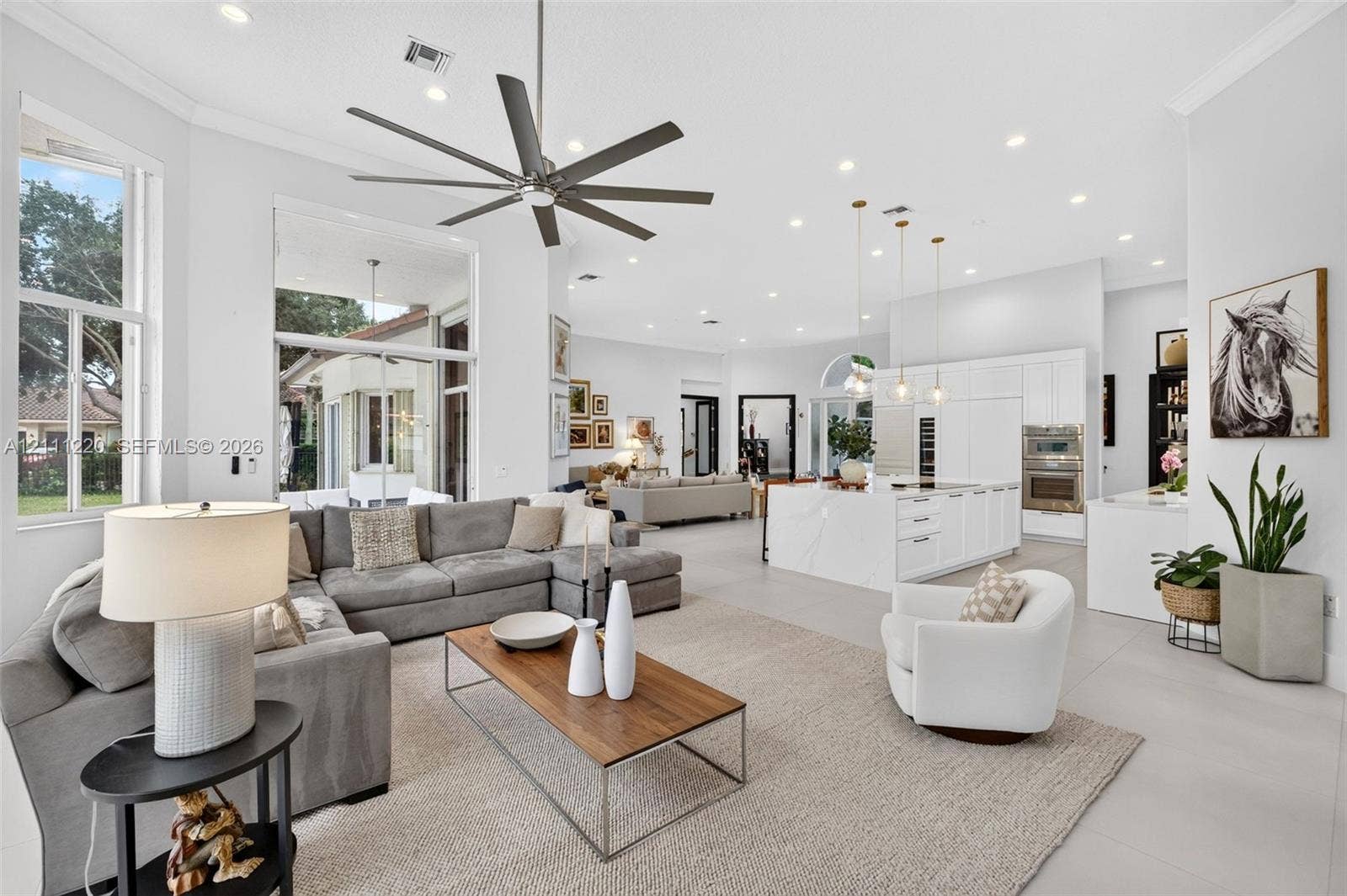 134 Dockside Terrace, Weston, FL 33327 Open-concept living area featuring high ceilings, recessed lighting, large-format tile flooring, a chef's kitchen with a waterfall island, and a multi-blade ceiling fan