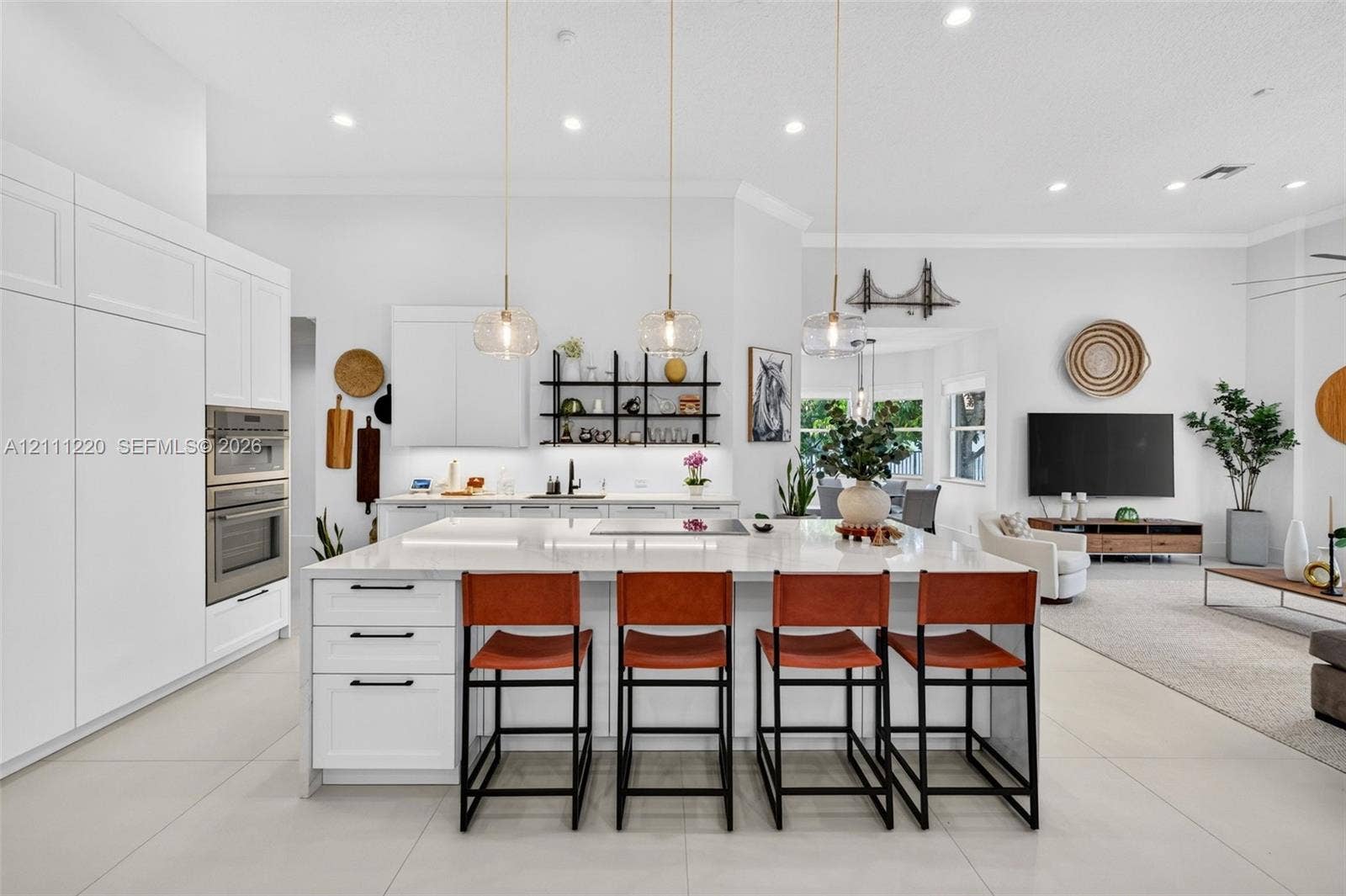 134 Dockside Terrace, Weston, FL 33327 Kitchen featuring white shaker-style cabinetry, a large central island with a stone countertop, built-in stainless steel double ovens, recessed lighting, and three suspended glass pendant lights
