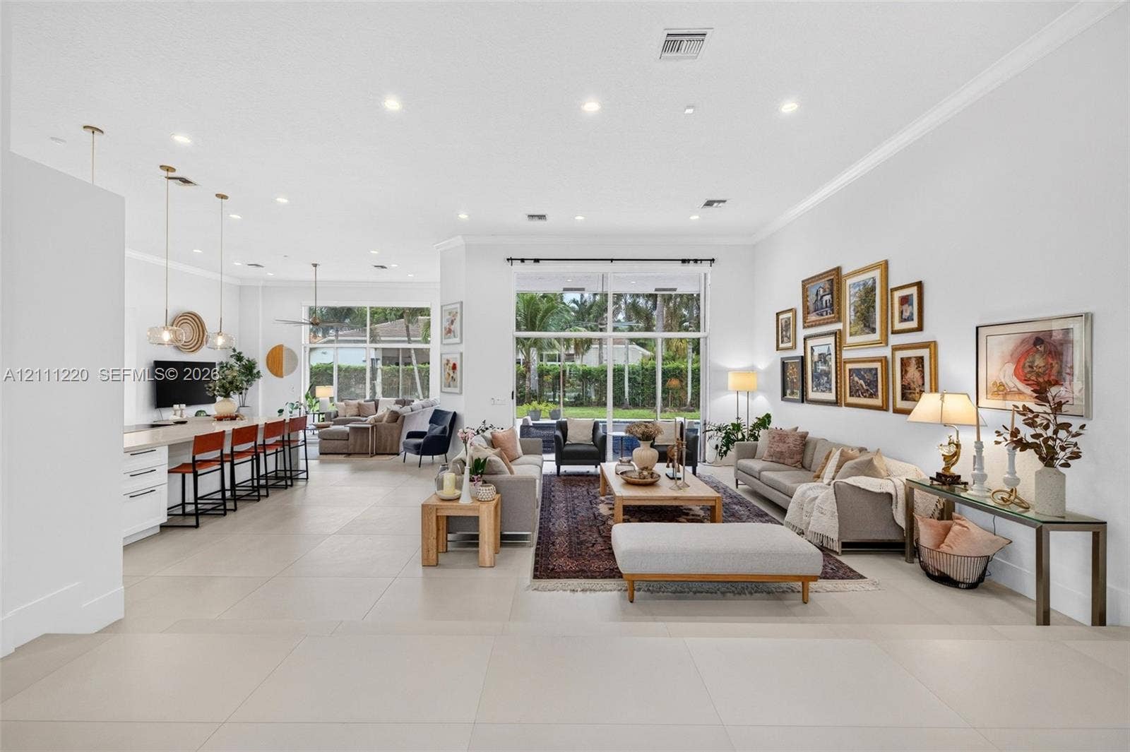 134 Dockside Terrace, Weston, FL 33327 Open-concept living space featuring large-format tile flooring, recessed lighting, floor-to-ceiling glass windows, and a built-in kitchen island with pendant lighting