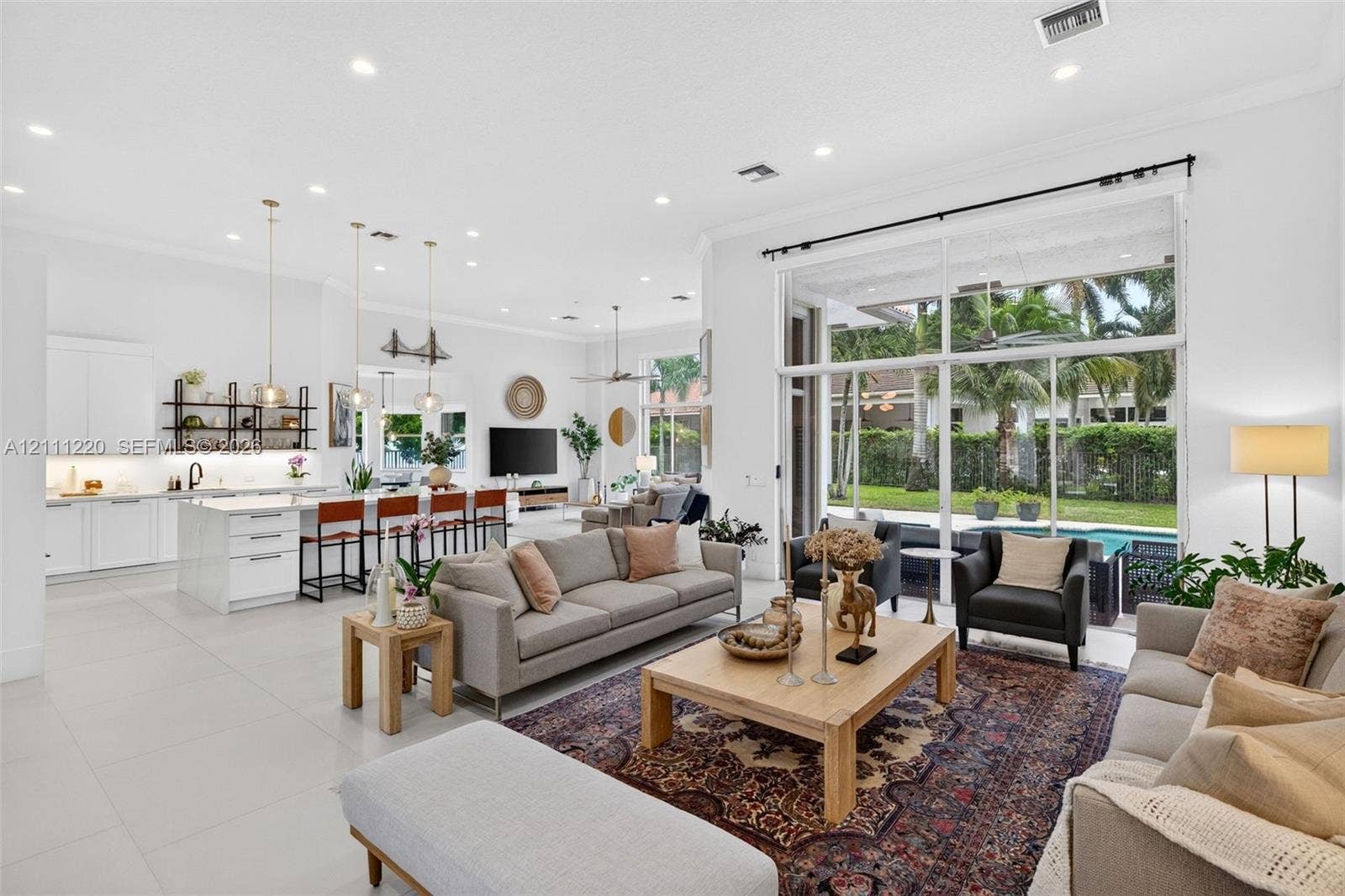 134 Dockside Terrace, Weston, FL 33327 Open-concept living area featuring large-format tile flooring, high ceilings with recessed lighting, kitchen with white cabinetry and a center island, and floor-to-ceiling glass sliding doors