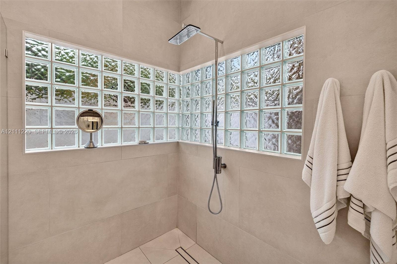 134 Dockside Terrace, Weston, FL 33327 Walk-in shower featuring large-format wall tile, glass block windows, a rectangular rainfall shower head, and a linear floor drain