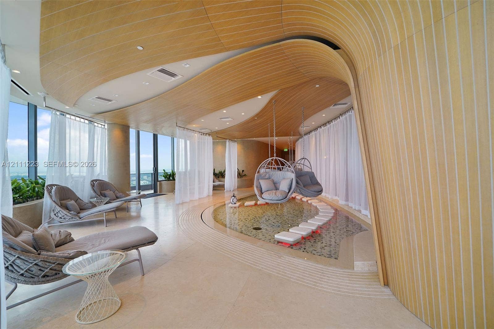 Curved wood-slat ceiling, integrated water feature with stepping stones, floor-to-ceiling glass windows, and recessed lighting