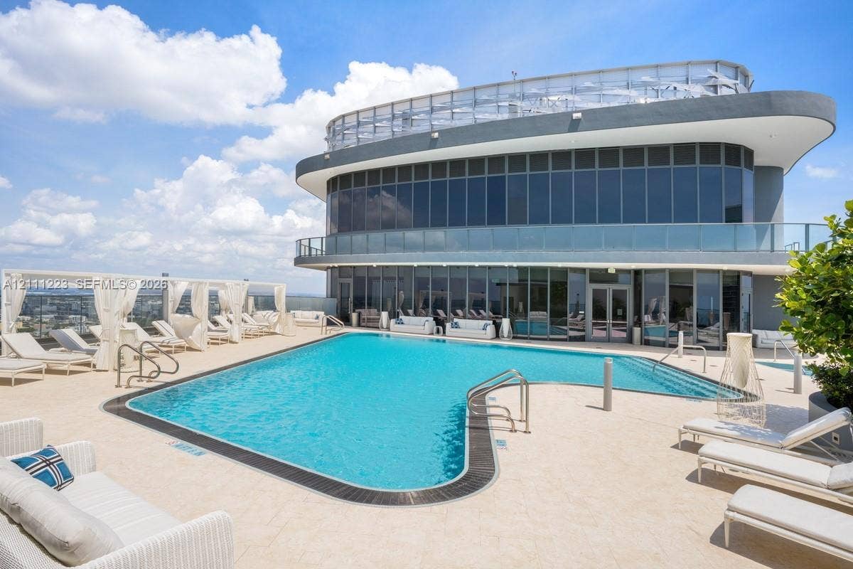 Rooftop swimming pool with metallic railings and light-toned hardscaping