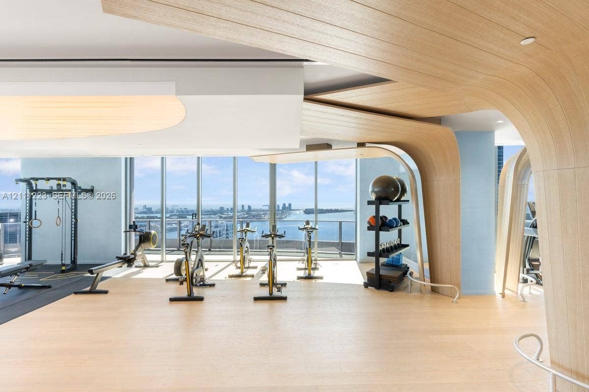 Floor-to-ceiling windows, custom wood-finished architectural archways, and light-toned wood-finish flooring