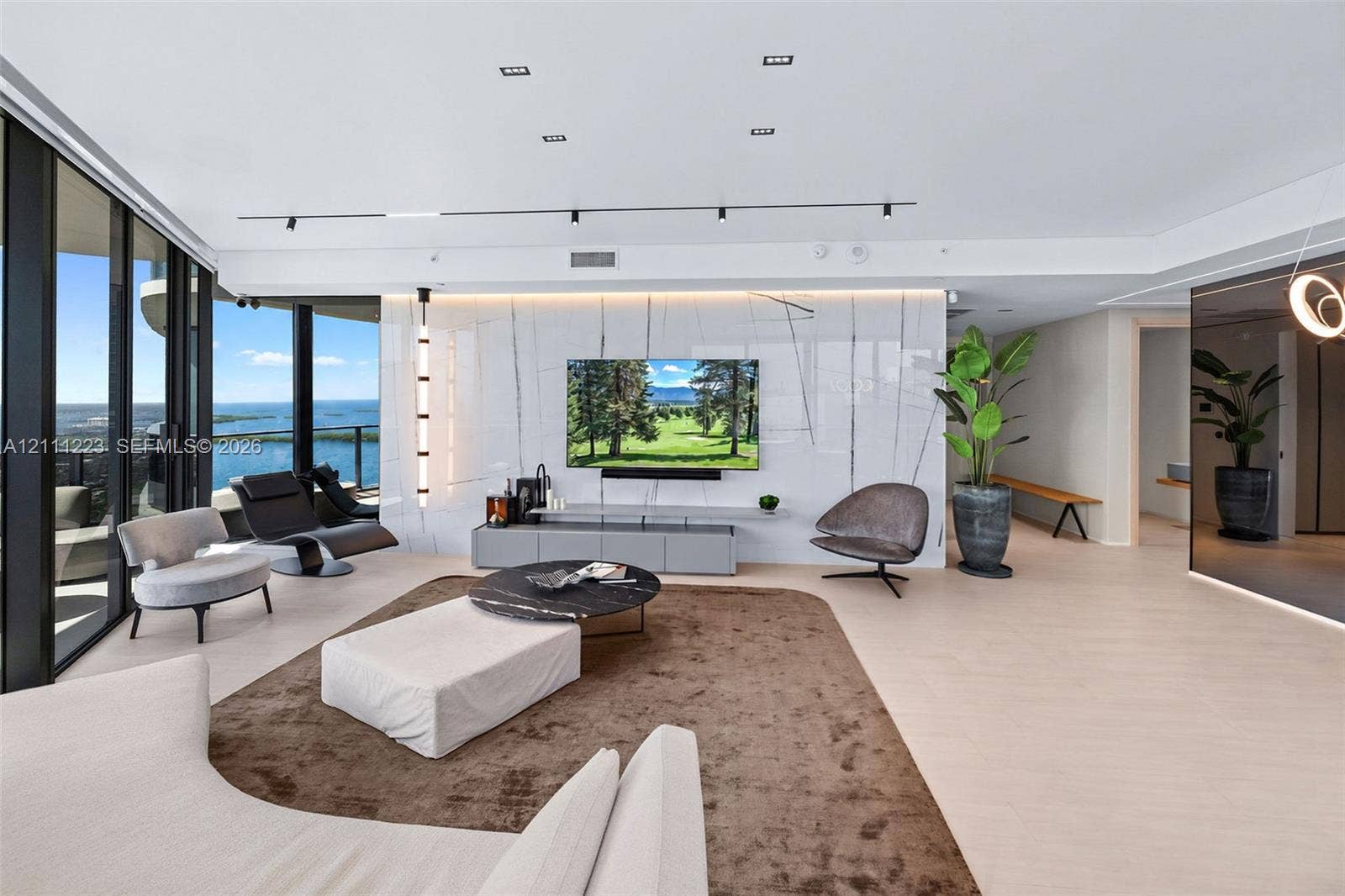Floor-to-ceiling glass wall, large-format stone-finish feature wall, recessed ceiling lighting, track lighting, and light-tone wood-finish flooring