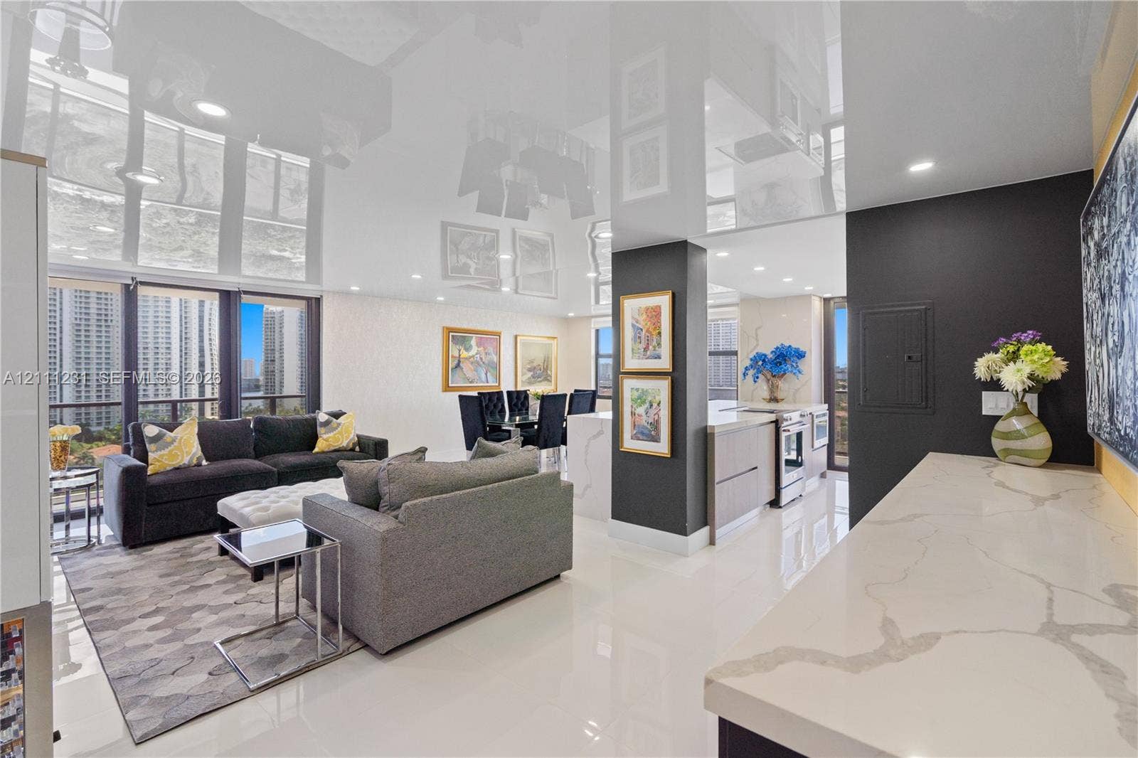 High-gloss reflective ceiling, stone countertop with waterfall edge, recessed lighting, floor-to-ceiling windows, and polished porcelain flooring