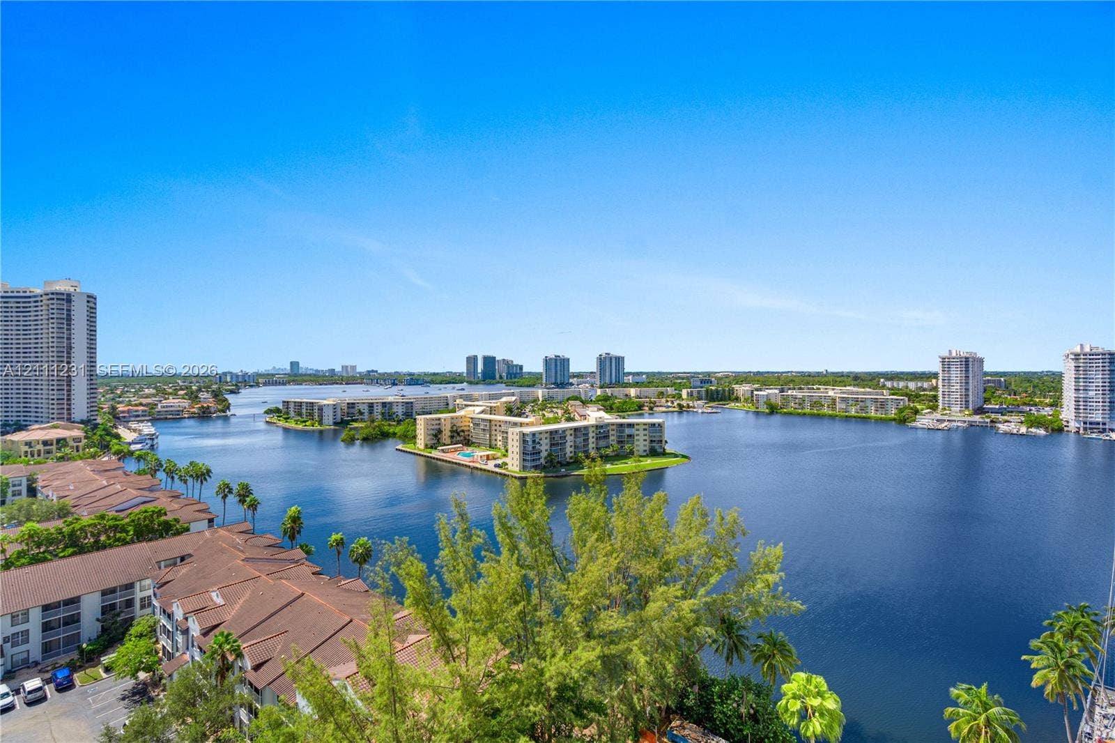 Panoramic waterfront perspective featuring expansive lake scenery, tropical landscaping, and mid-rise residential architecture