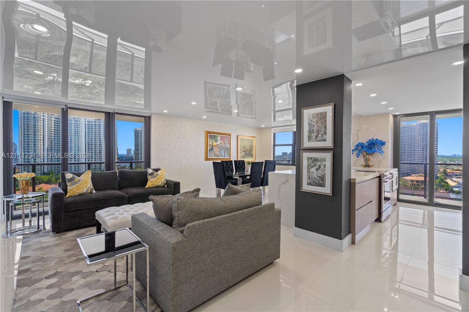High-gloss reflective ceiling, expansive floor-to-ceiling windows, polished tile flooring, recessed lighting, and kitchen peninsula featuring stone-finish countertop