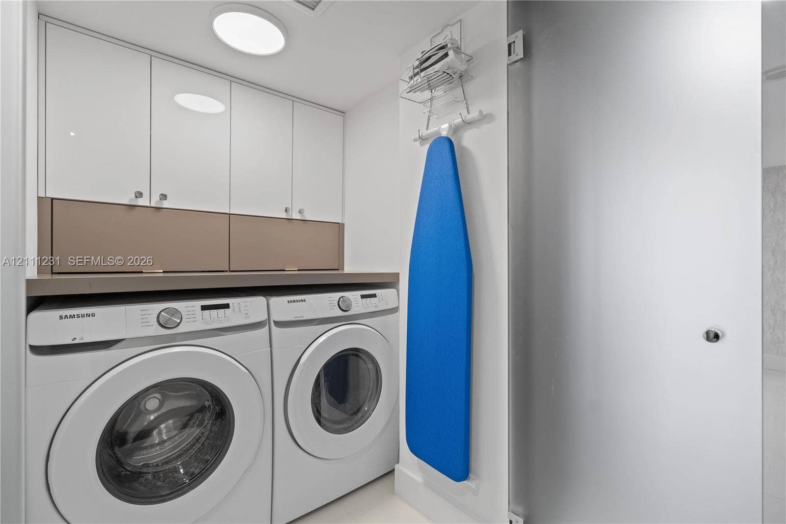 Laundry area featuring white high-gloss upper cabinetry, solid surface countertop, and flush-mount ceiling lighting