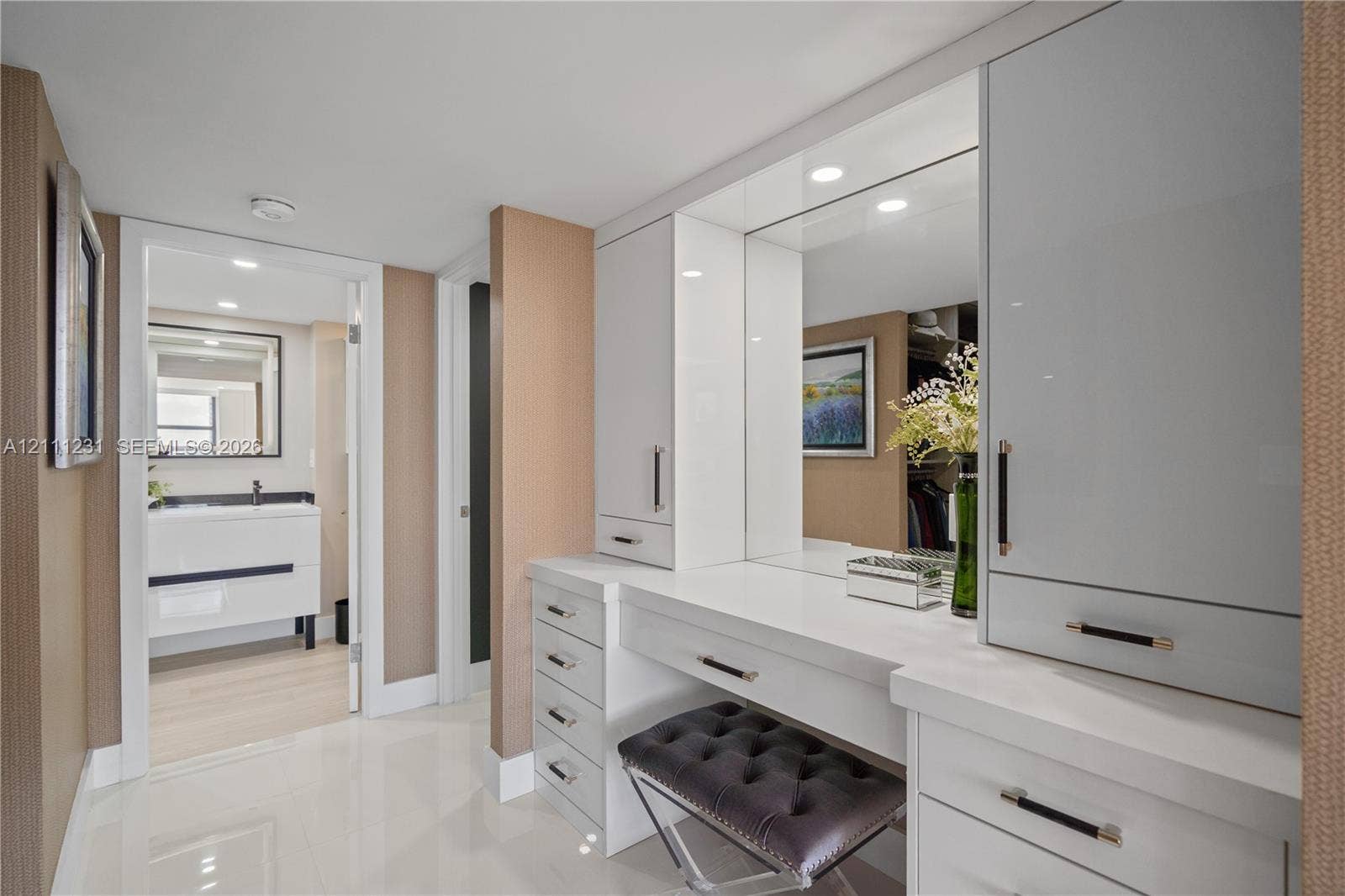 Custom built-in vanity featuring white high-gloss cabinetry, integrated lighting, expansive countertop, and polished metal hardware
