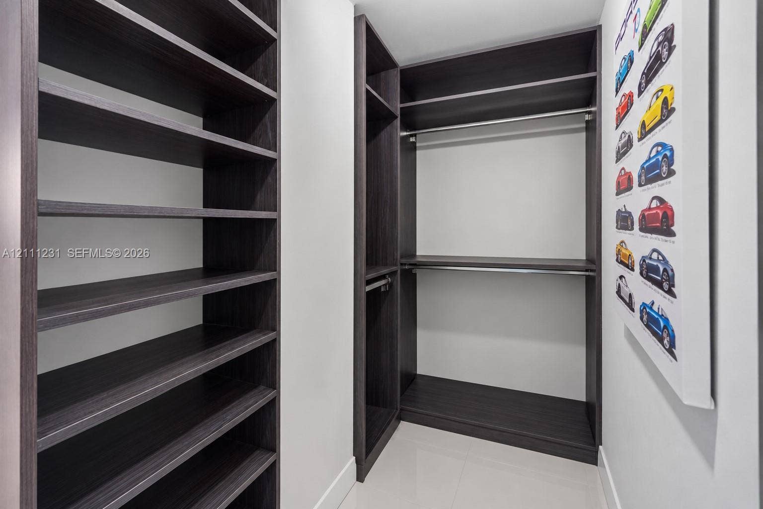Custom walk-in closet featuring dark wood-finish shelving, integrated hanging rods, and multiple open storage compartments