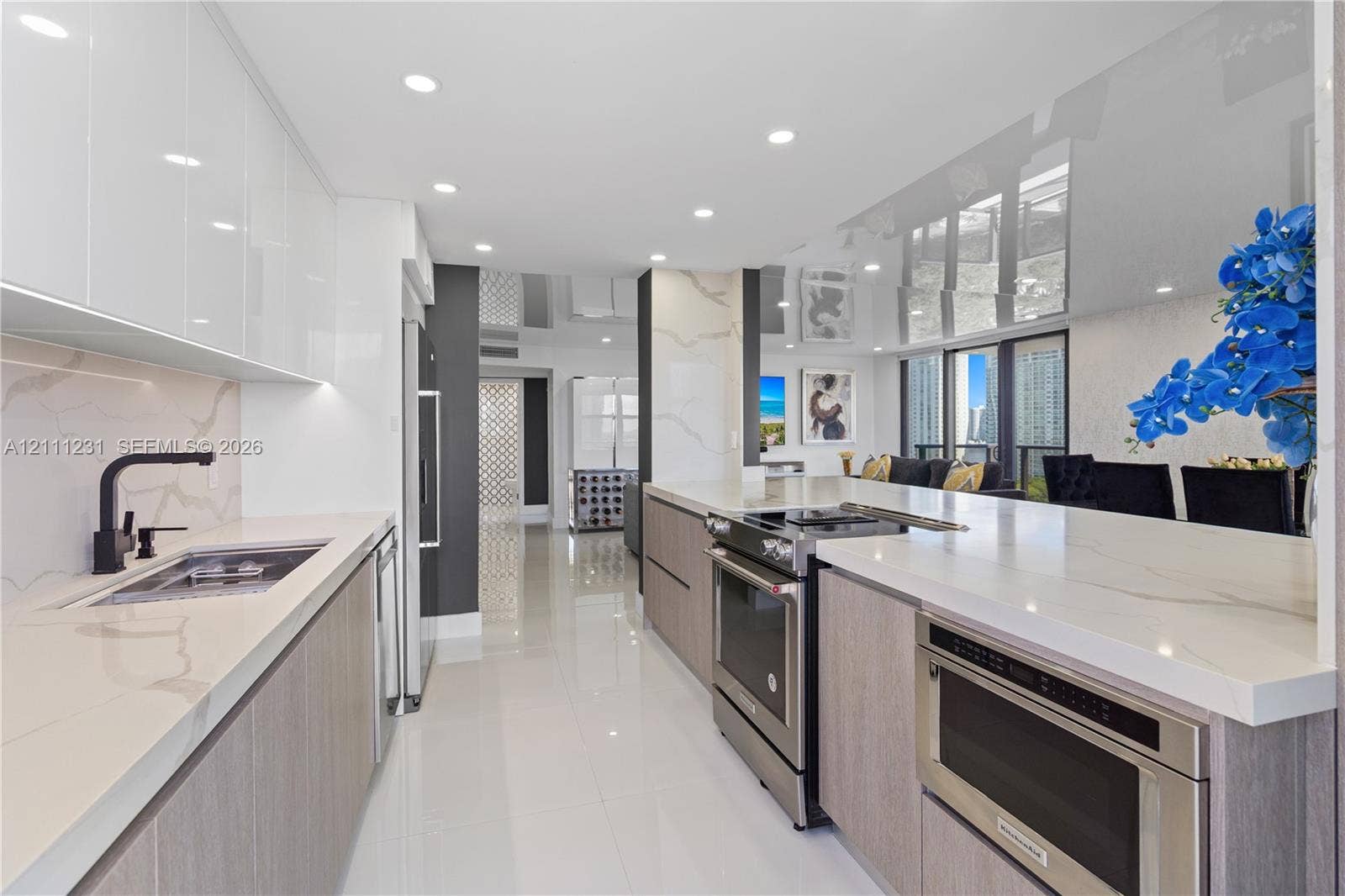 Modern kitchen featuring high-gloss cabinetry, stone countertops, stainless steel appliances, matte black fixtures, and recessed lighting