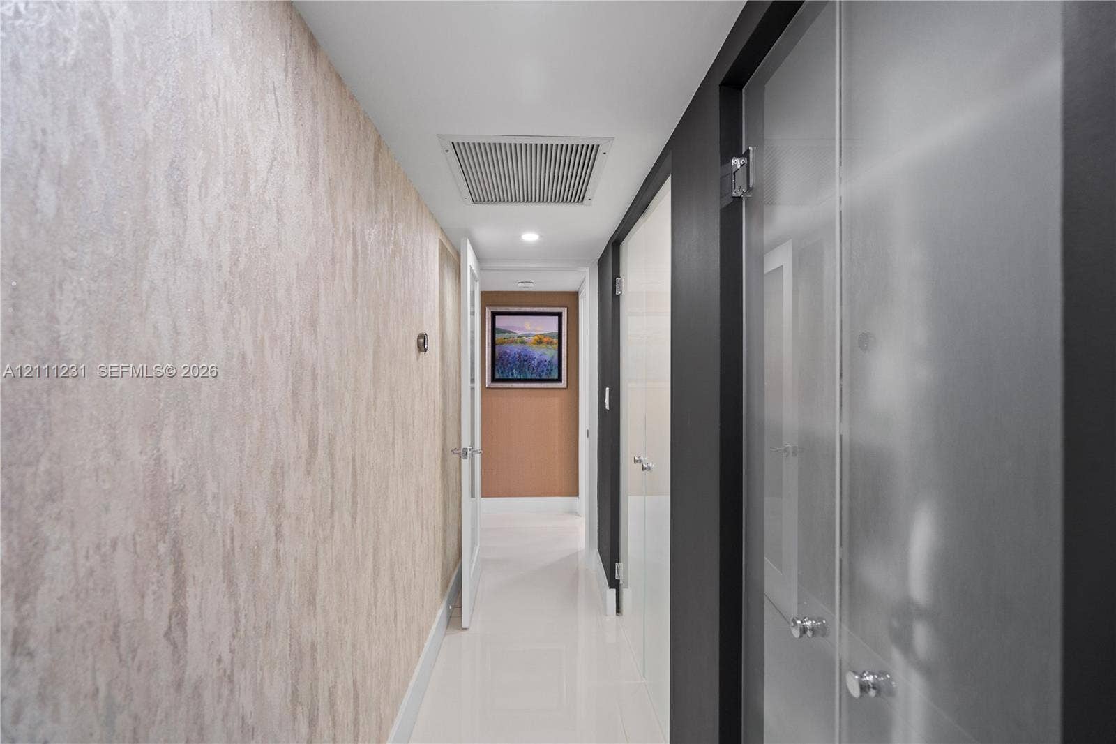 Hallway featuring textured wallpaper, high-gloss tile flooring, and frosted glass panel doors
