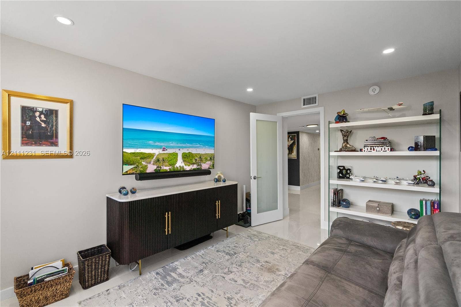 Interior space featuring recessed lighting, smooth surface flooring, a built-in glass-shelf display unit, and a door with a frosted glass panel