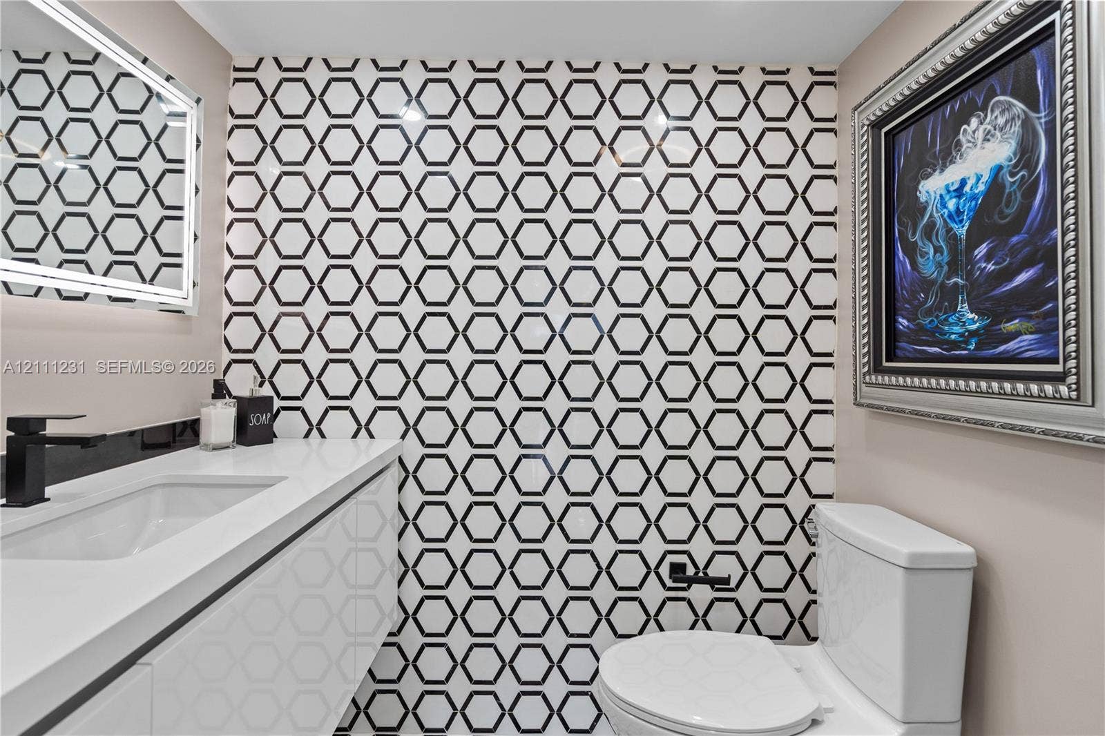 Hexagonal geometric wall tile, modern white floating vanity with a seamless countertop, integrated rectangular sink, matte black faucet, and backlit LED vanity mirror
