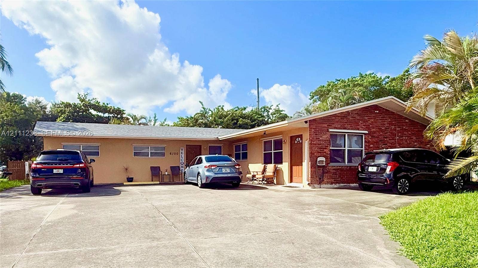 6100 SW 37th Street, Davie, FL 33314 Single-story exterior featuring a mix of brick and stucco siding, a low-pitched roof, an expansive concrete driveway, and multi-paned windows