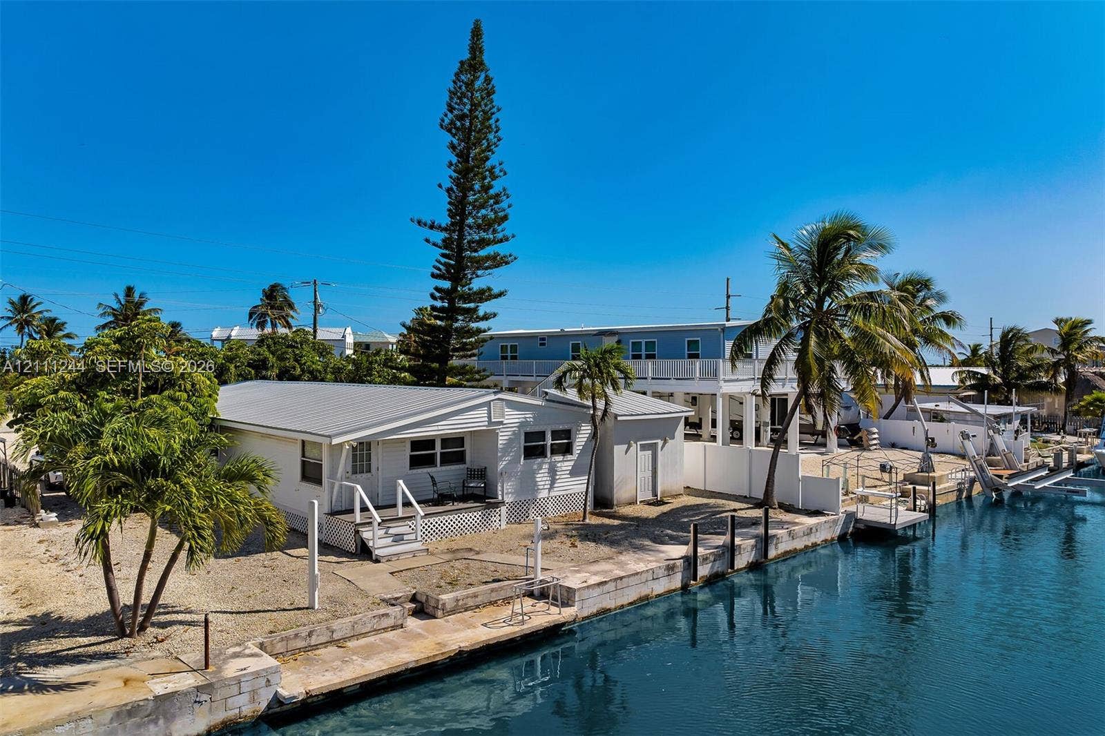 Waterfront property featuring a concrete seawall, private dock, metal roof, and exterior stairs
