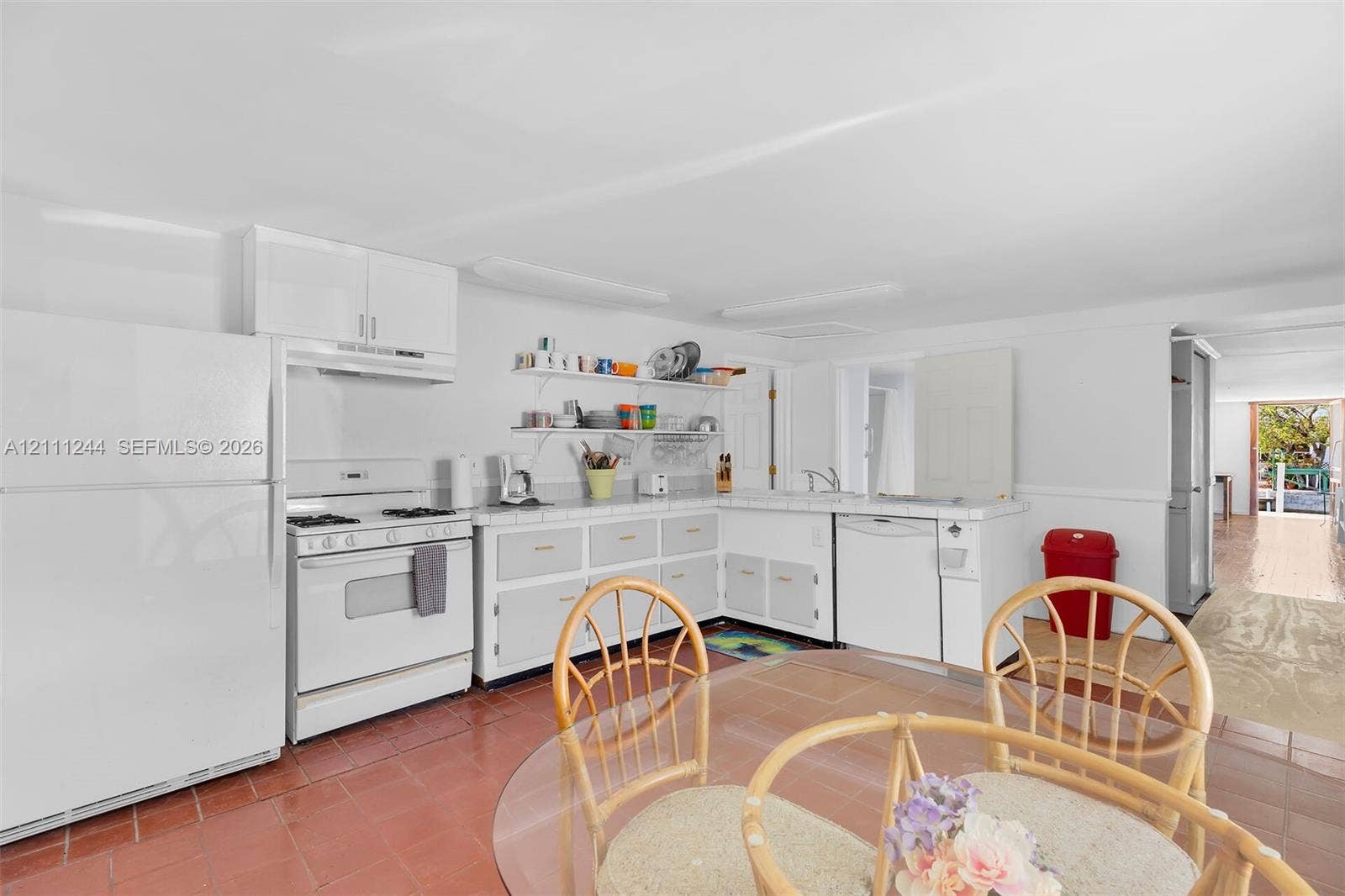 Kitchen featuring white cabinetry, tile countertops, tile flooring, wall-mounted shelving, and white appliances