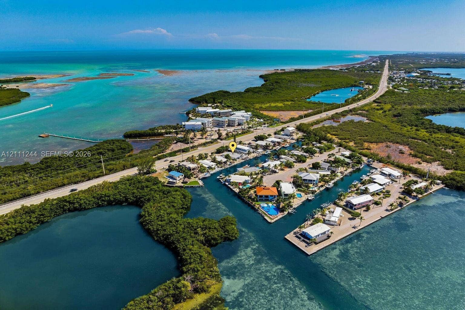 Aerial perspective of a coastal property featuring direct water access, a canal-front location, and surrounding open water scenery