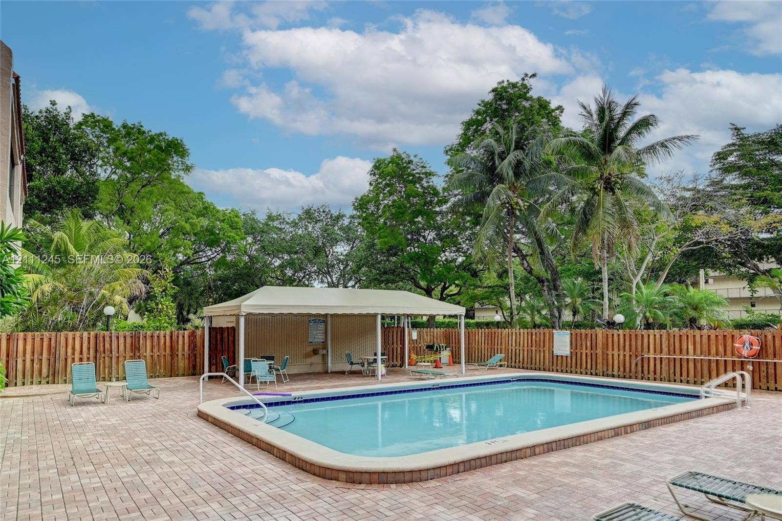 6800 Cypress Road, #506, Plantation, FL 33317 In-ground swimming pool with surrounding brick-paver decking, covered pavilion, and privacy fencing