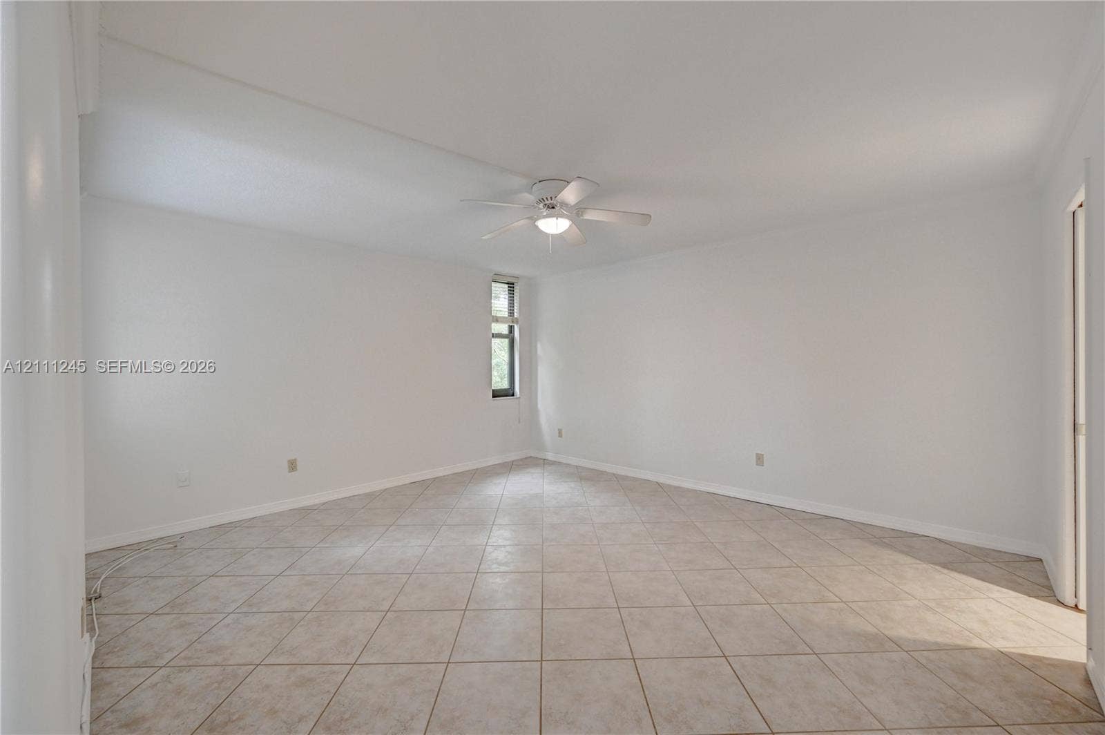 6800 Cypress Road, #506, Plantation, FL 33317 Spacious interior featuring light-colored tile flooring, neutral wall tones, a ceiling fan with integrated lighting, and a vertical window