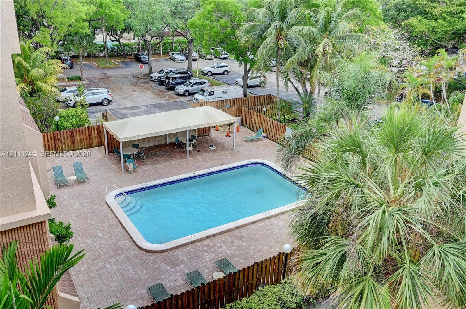 6800 Cypress Road, #506, Plantation, FL 33317 Swimming pool with concrete pavers, covered pergola, and surrounding perimeter wood fencing
