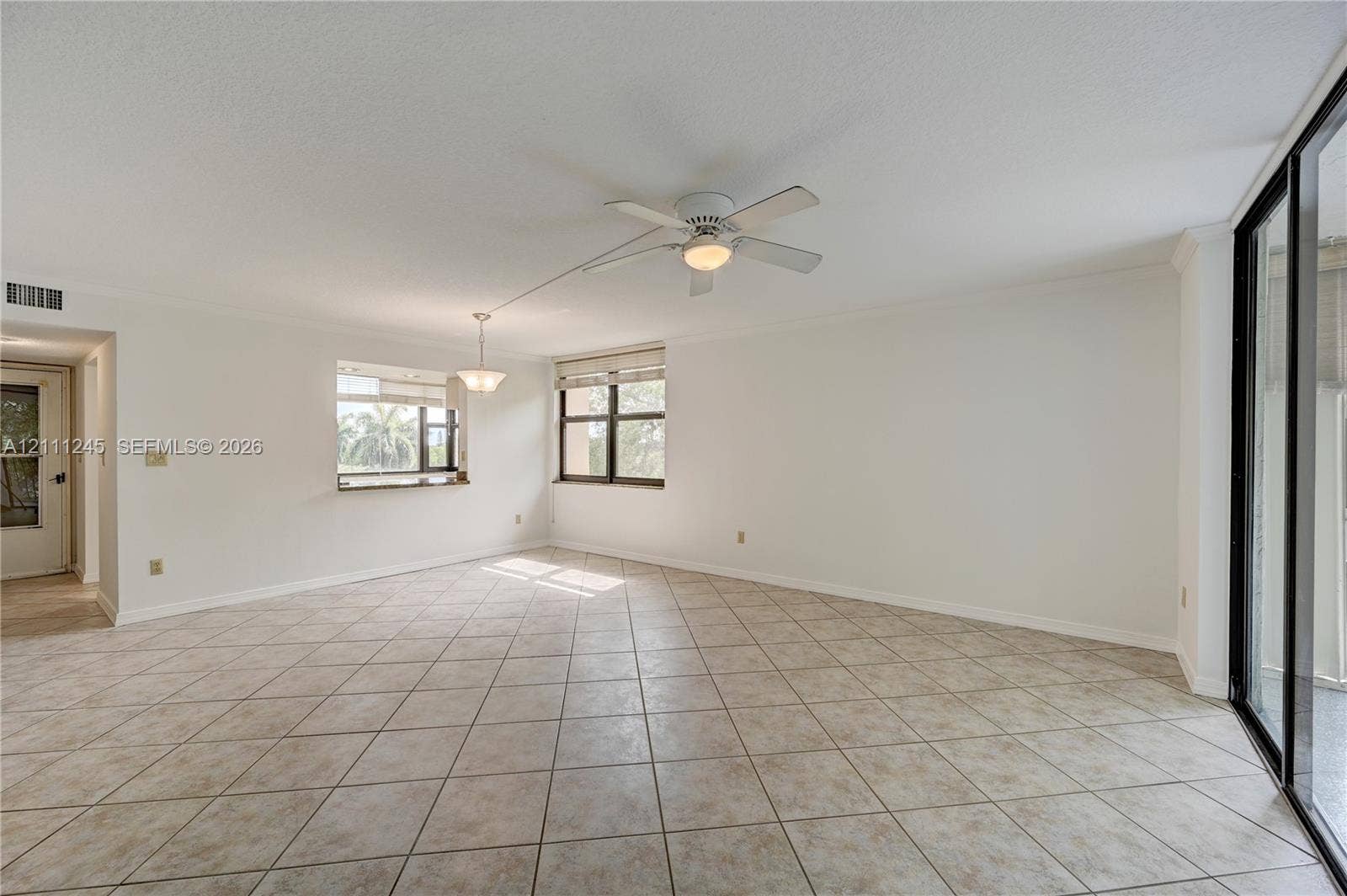6800 Cypress Road, #506, Plantation, FL 33317 Open floor plan featuring tile flooring, multi-pane windows, a ceiling fan with integrated light, and sliding glass doors